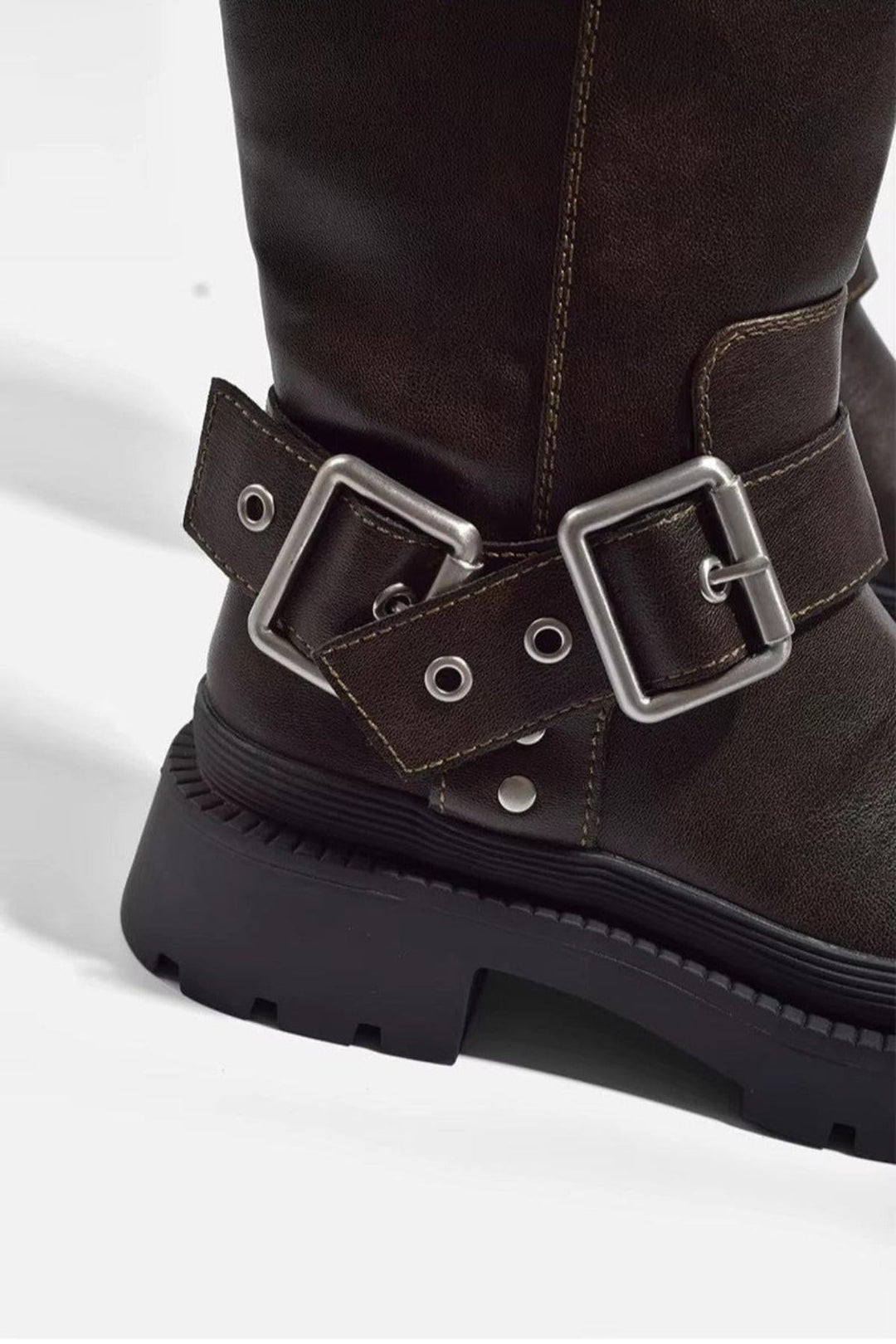 Brown women's knee-high flat boots featuring a trendy chunky sole. Versatile for modern winter outfits.