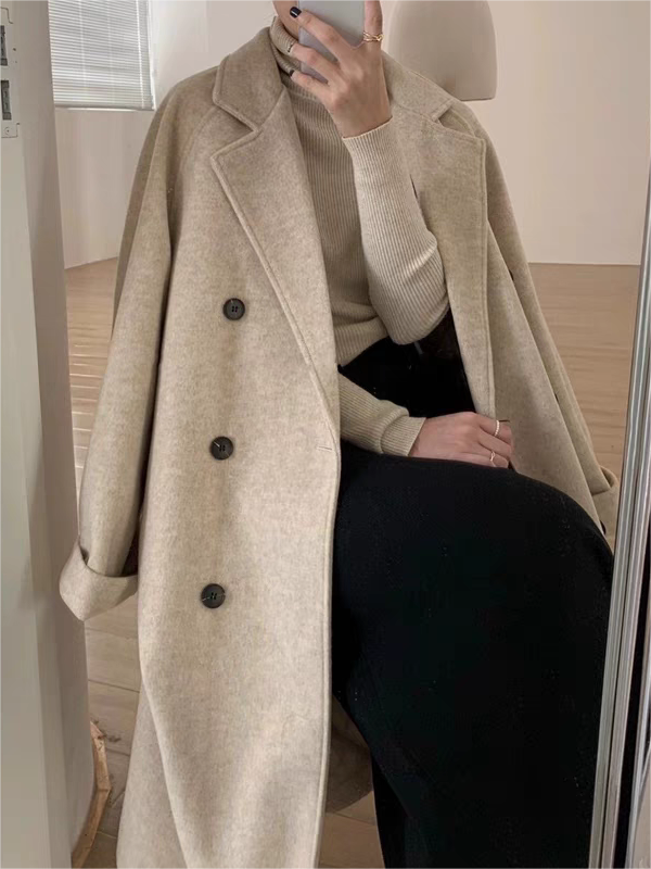 Close-up of a women's elegant belted long coat, showing the sophisticated lapel collar and a tie-waist detail.