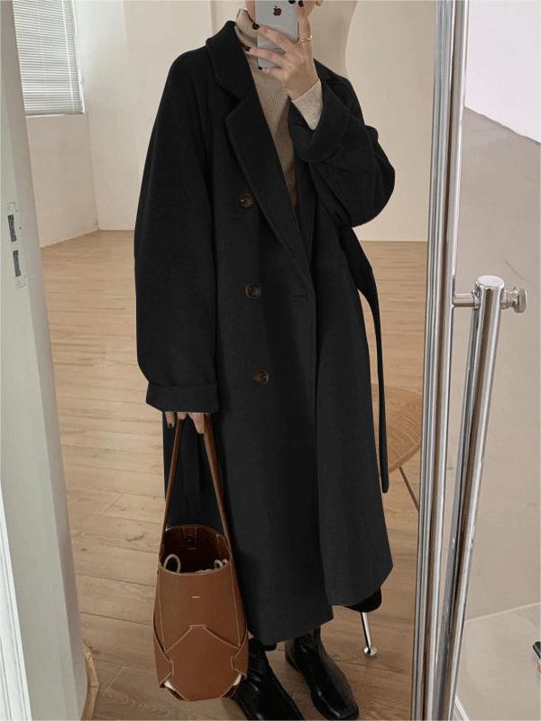 Studio shot of a women's classic belted long coat, displaying its full length, lapel collar, and winter apparel details.