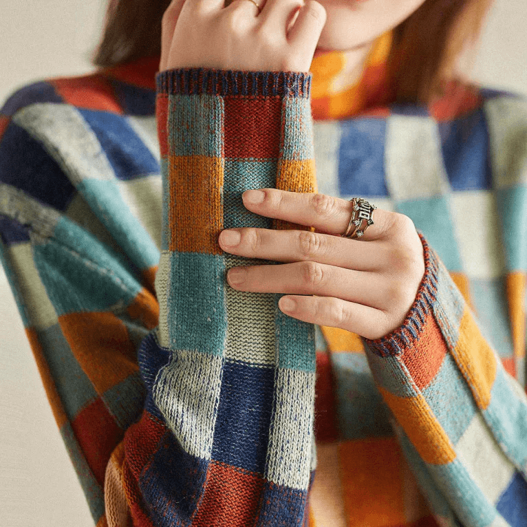 Woman enjoying a warm cozy knit high collar jumper outdoors. Perfect long sleeve pullover sweater for winter style.