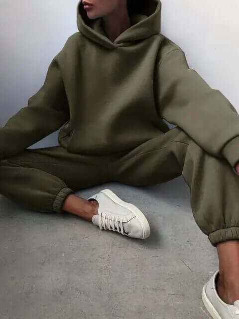 Woman relaxing in a cozy oversized tracksuit set. Comfortable hoodie & pants, perfect for loungewear.