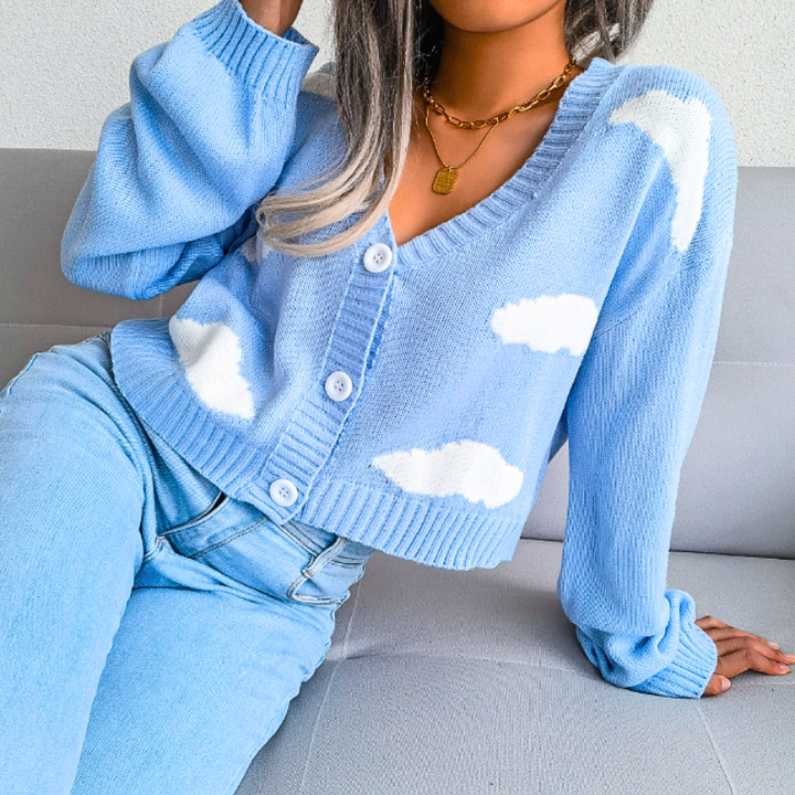 Pink women's cropped cardigan with unique cloud print. Stylish V-neck button-up top.