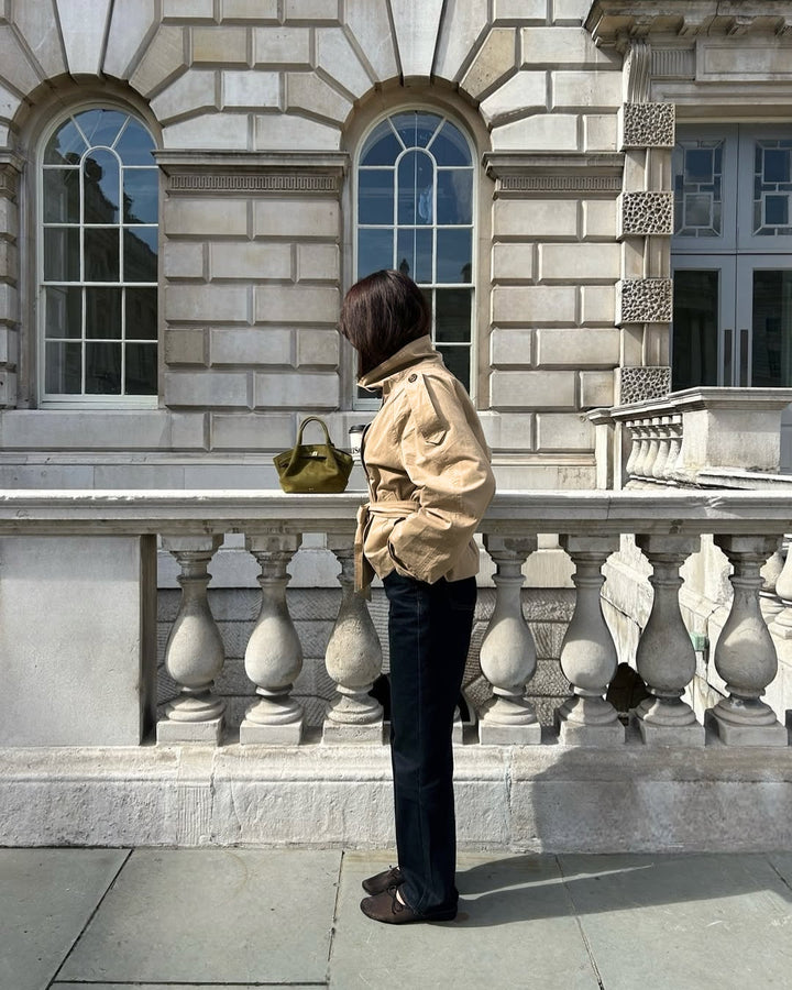 Classic women's outerwear: cropped double-breasted trench coat with a fashionable belt.