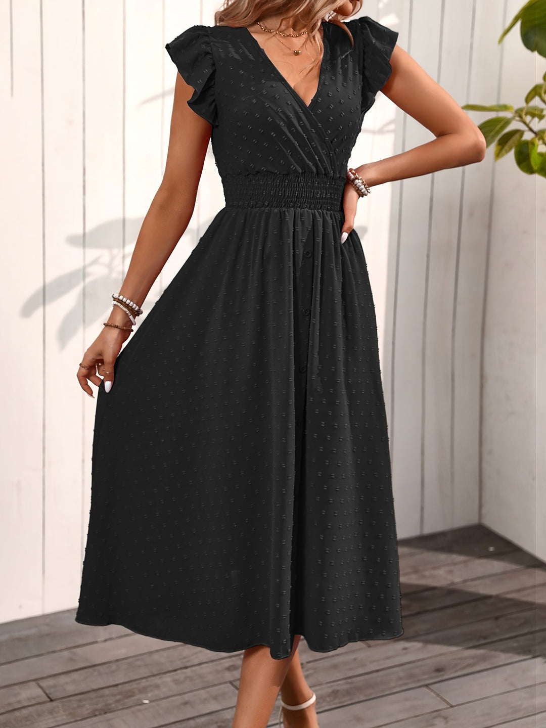 Flowy women's black midi dress, V-neck, ruffle sleeves, smocked waist, and dotted pattern. Perfect for day.