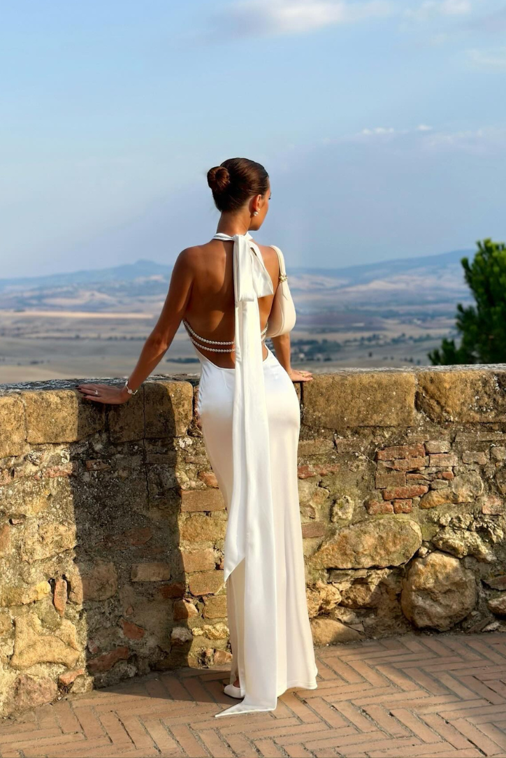 Flowy white maxi dress with elegant pearl details, a beautiful formal and wedding guest dress for women.