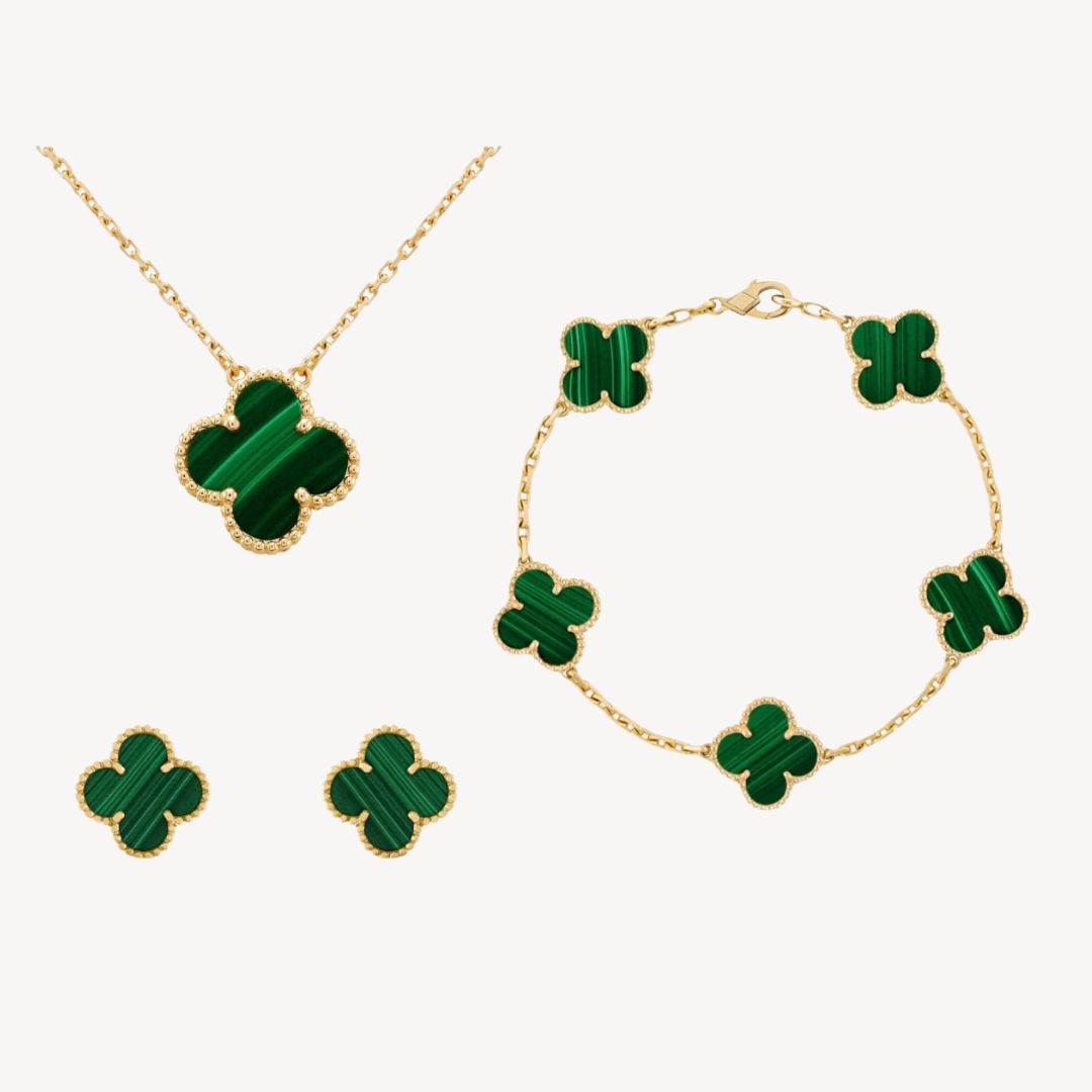 Close-up of women's gold-tone clover jewelry set featuring a necklace, bracelet, & matching earrings. Fashionable.