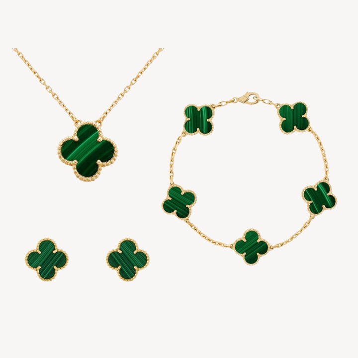 Close-up of women's gold-tone clover jewelry set featuring a necklace, bracelet, & matching earrings. Fashionable.