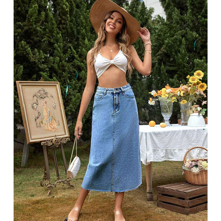 Close-up of the frayed hem on a women's high-waisted blue denim maxi skirt, showing detail.