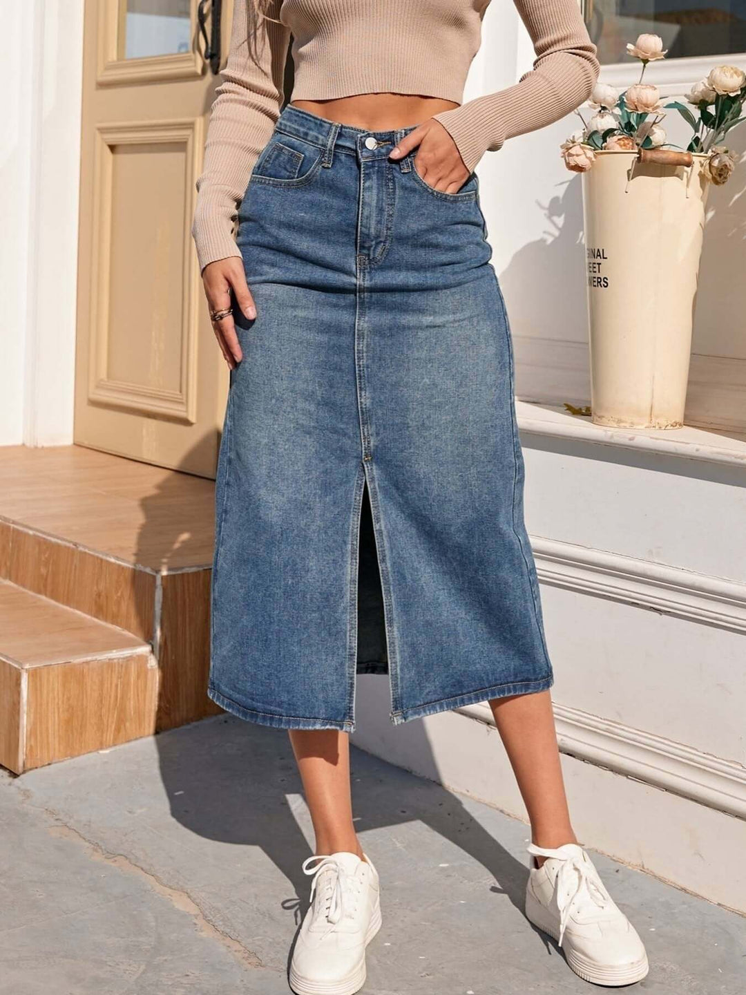Women's high-waisted blue denim midi skirt with stylish front slit, perfect for casual everyday wear.