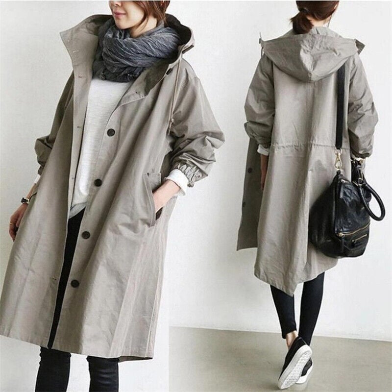 Full-length view of a woman in a stylish lightweight hooded rain trench coat, ready for travel.