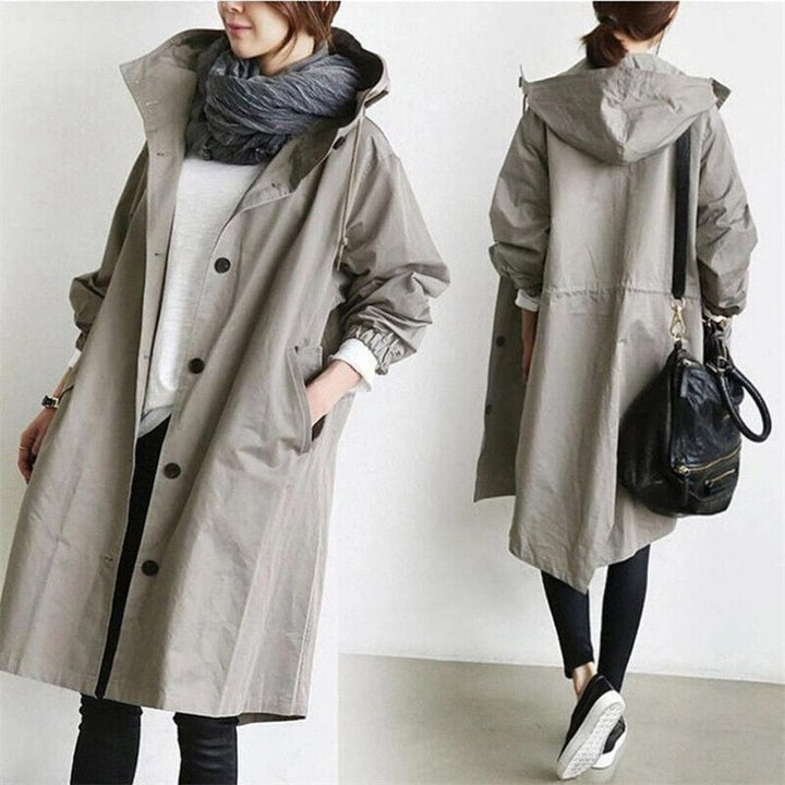 Full-length view of a woman in a stylish lightweight hooded rain trench coat, ready for travel.