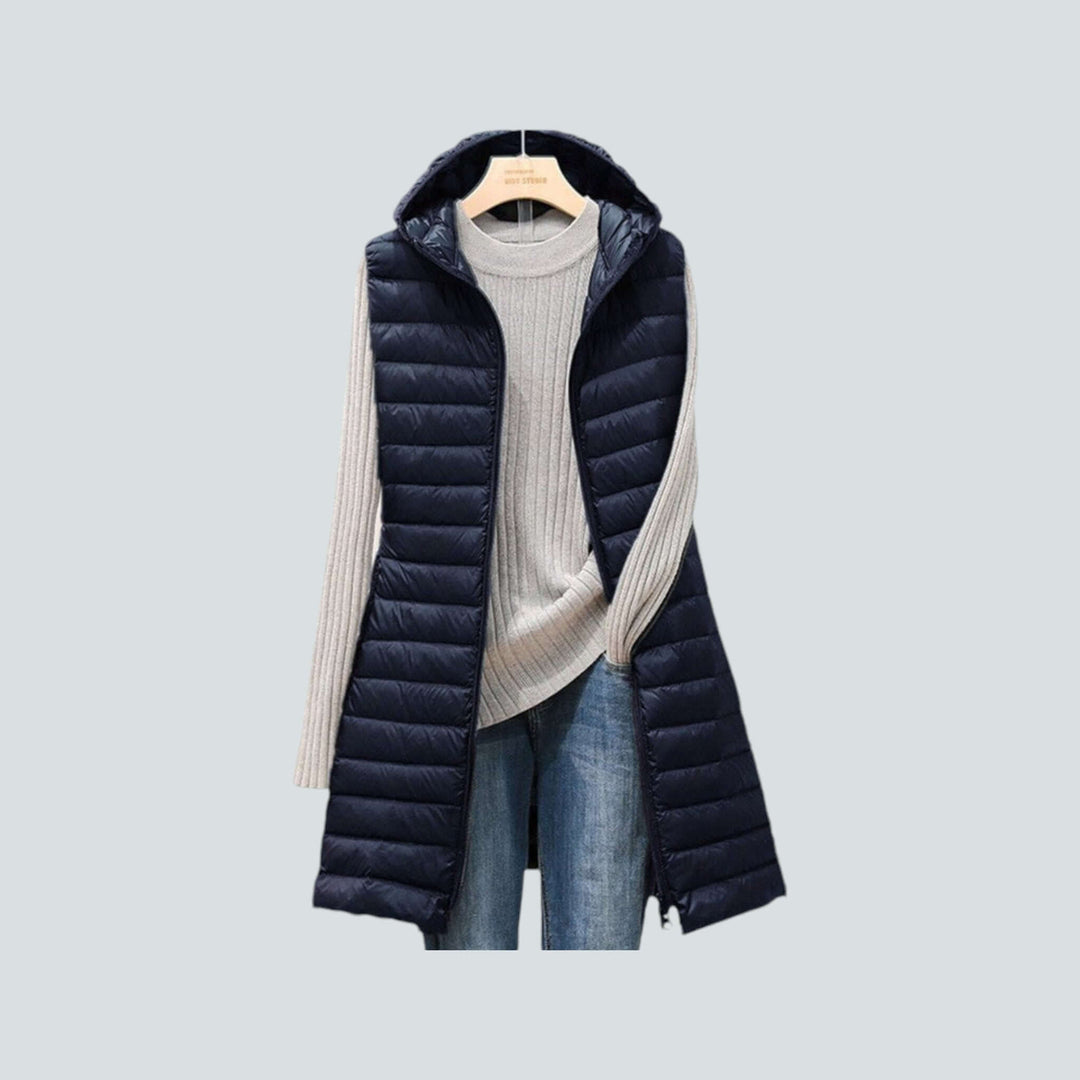 Chic women's long hooded puffer vest, featuring a quilted design and cozy sleeveless warmth for cold weather.