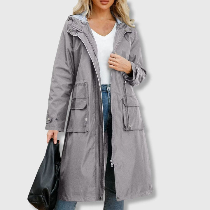Women's full-length waterproof rain jacket with adjustable hood & drawstring waist. Essential all-weather outerwear.