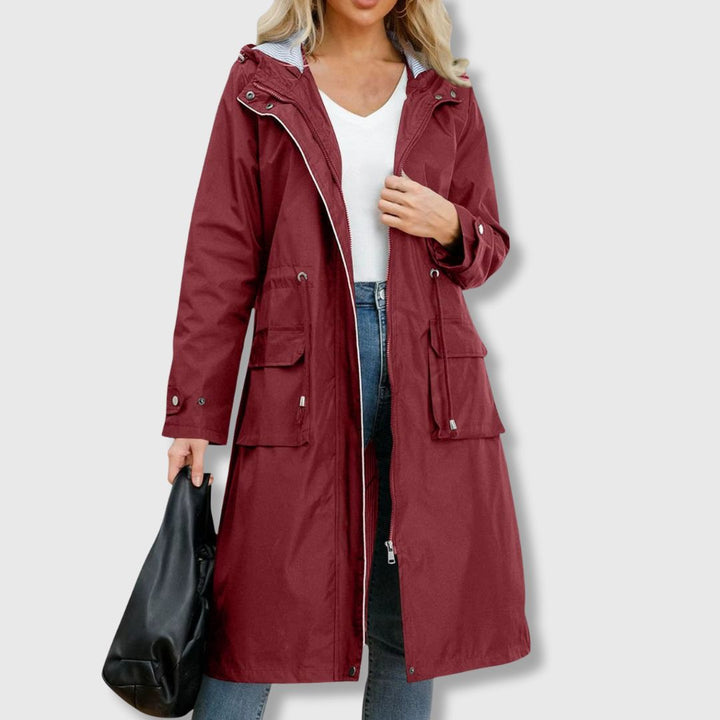 Chic women's long hooded rain jacket, waterproof for protection, with a flattering drawstring waist. All-weather wear.