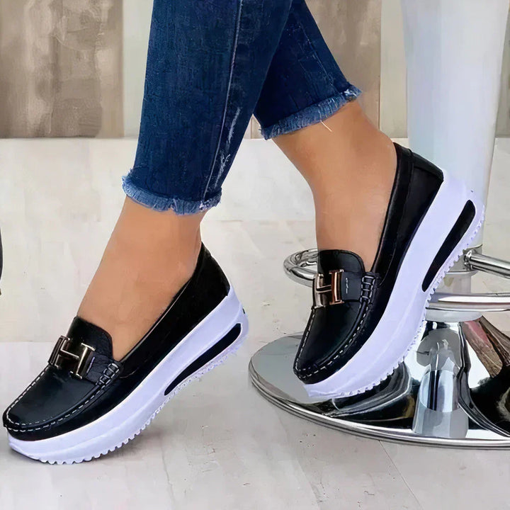 Black platform slip-on loafers for women, offering a modern, comfortable, and dressy flat shoe option.