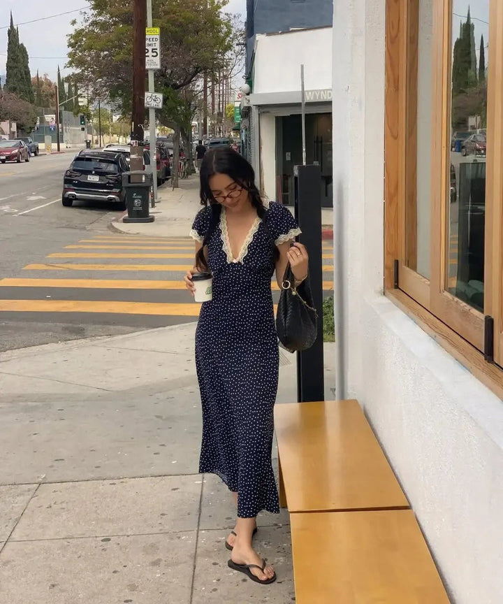 Women's navy polka dot midi summer dress with flutter sleeves. Lightweight and elegant for casual day wear.