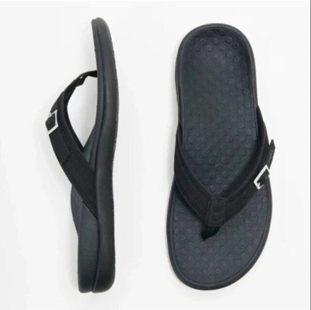 Woman wearing supportive arch support flip flops, walking on a beach, highlighting summer fashion and comfort.