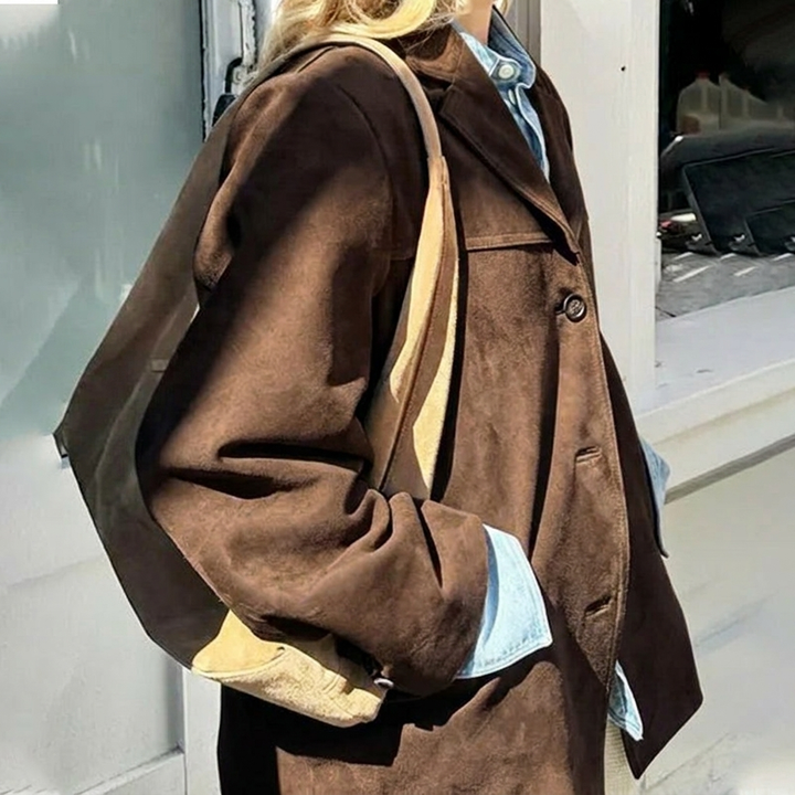 Model wears a women's oversized brown blazer, showcasing its relaxed fit & notched lapel. Effortless workwear style.