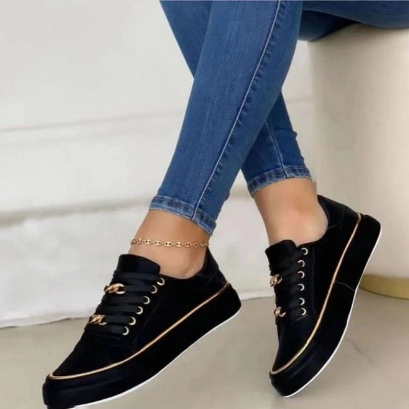 Fashionable women's platform sneakers with bold gold chain detail, low top design, and thick sole.