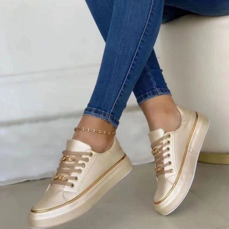Platform shoes for women, featuring a distinctive gold chain and sleek white low-top design.