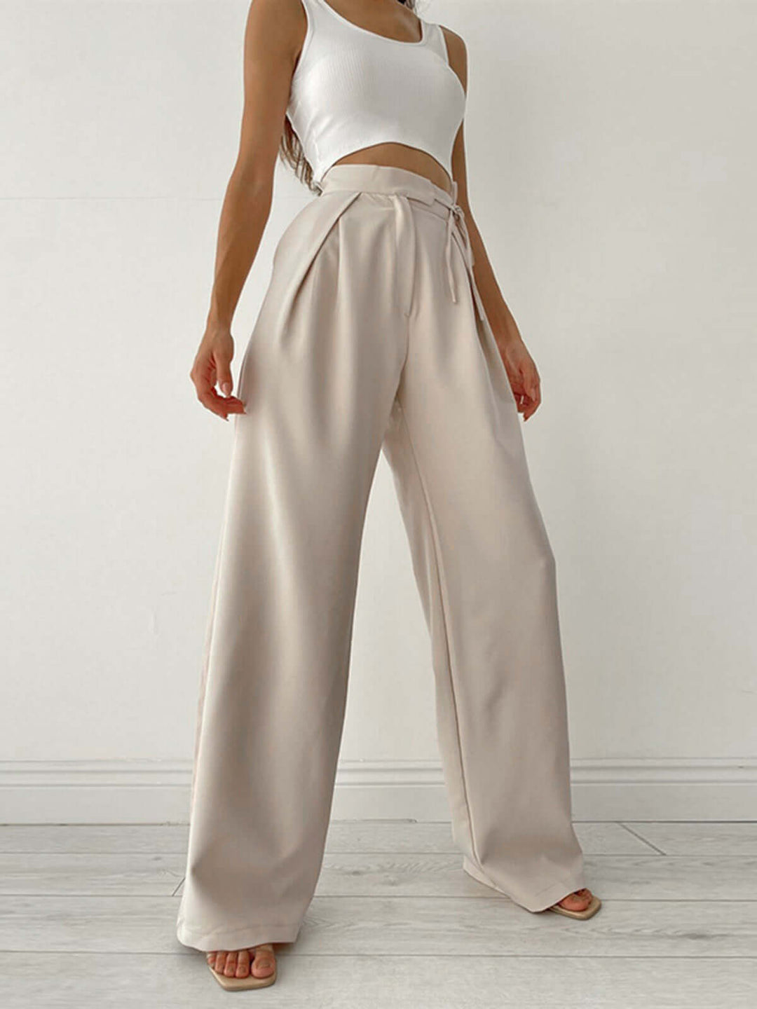Beige women's high-waist wide-leg palazzo pants, loose fit, pleated for a stylish summer look.
