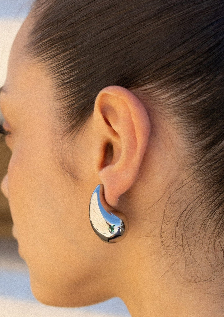 Pair of women's polished teardrop dangle earrings, shiny stainless steel elegant jewelry with secure hook.