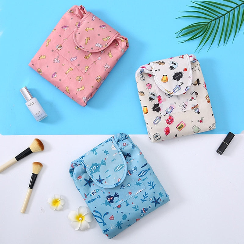 Flat lay of an open drawstring makeup organizer bag with various beauty items inside.