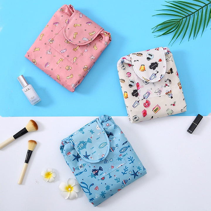Flat lay of an open drawstring makeup organizer bag with various beauty items inside.