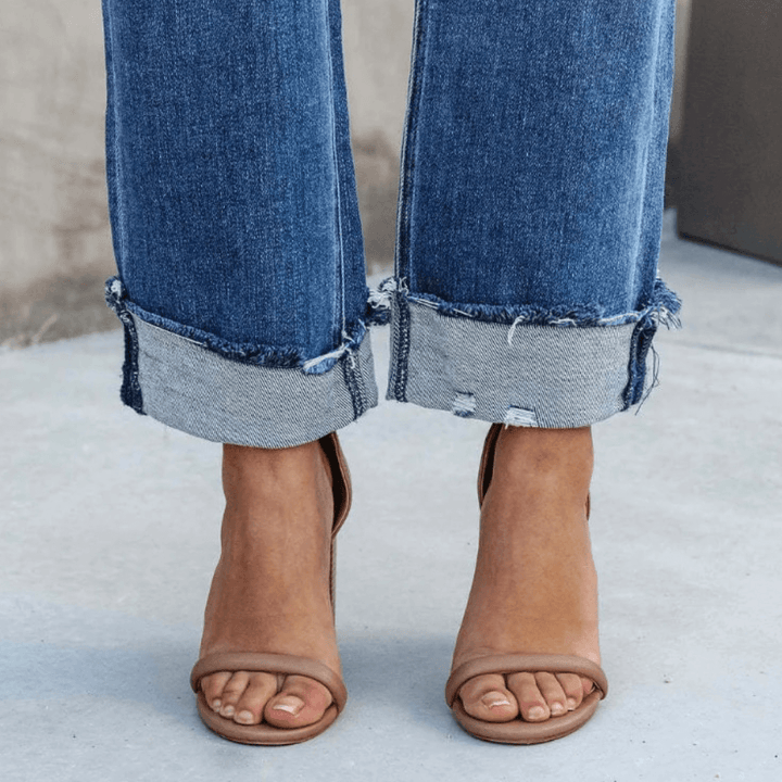 Stylish women's blue denim jeans, relaxed fit, showcasing a fashionable irregular waist. Great for casual wear.