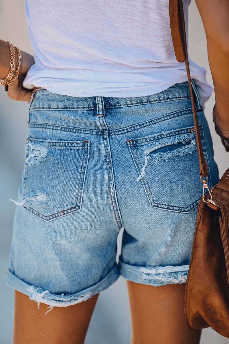 Textured women's denim shorts with trendy rips and frayed fringes, great for warm weather.