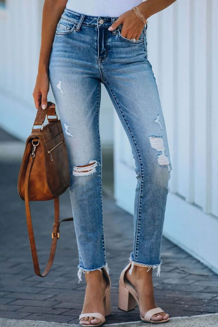 Distressed blue denim straight leg jeans for women. Trendy ripped style for casual everyday fashion.