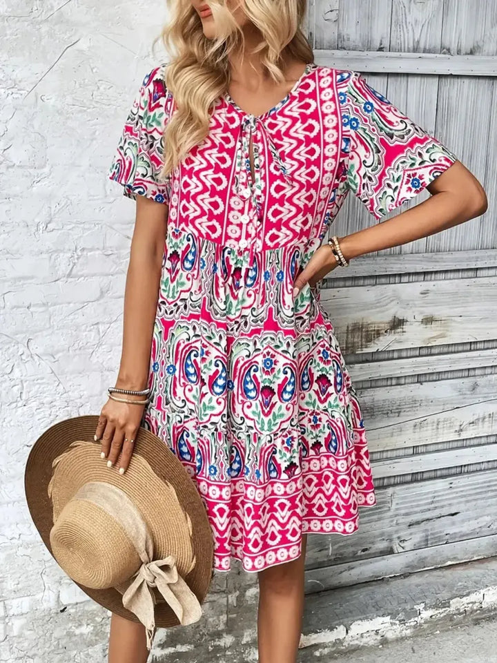 Stylish women's summer mini dress with short sleeves, ideal for vacation wear or day events. Tie neck detail.