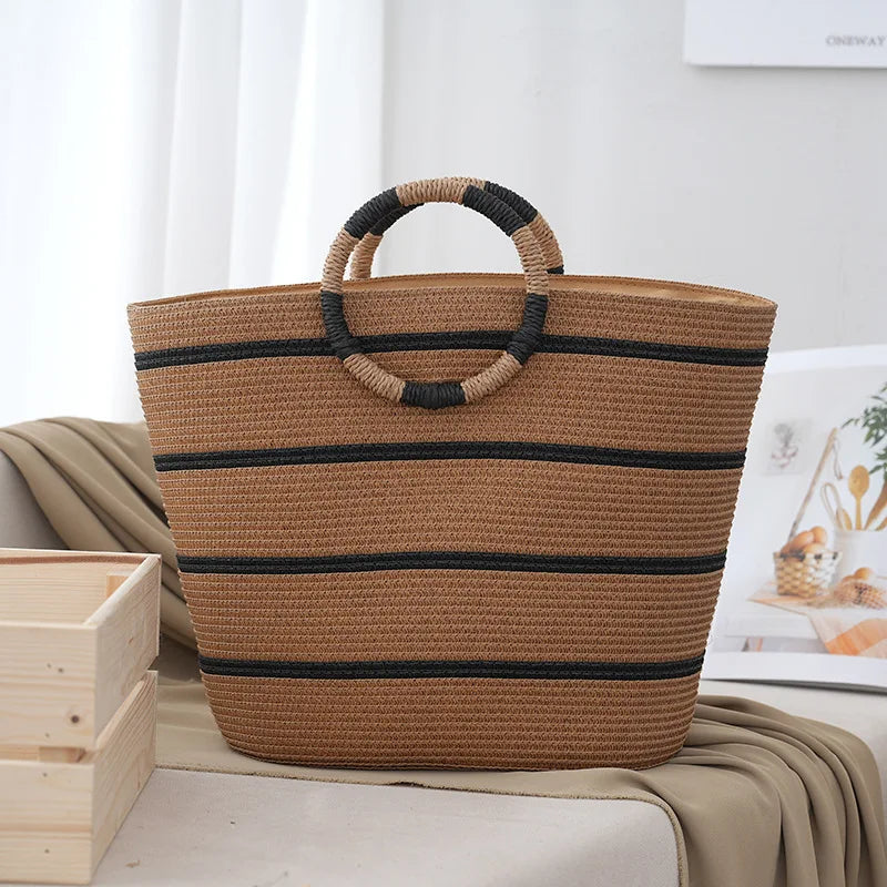 Women's striped woven beach tote bag on sand, packed with essentials. Spacious & trendy for summer trips.