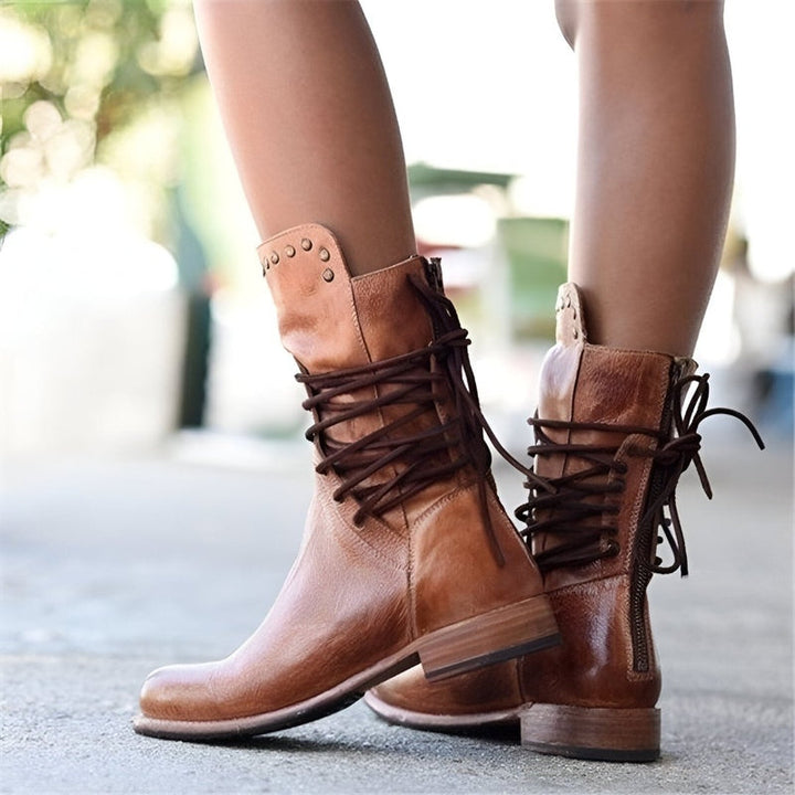 Woman confidently striding in trendy studded lace-up mid-calf boots with low heel, showcasing autumn fashion.