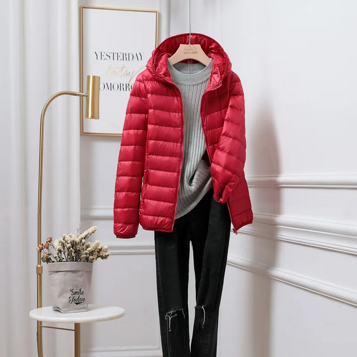 Display of various colored ultralight women's hooded puffer jackets, stylish & versatile.