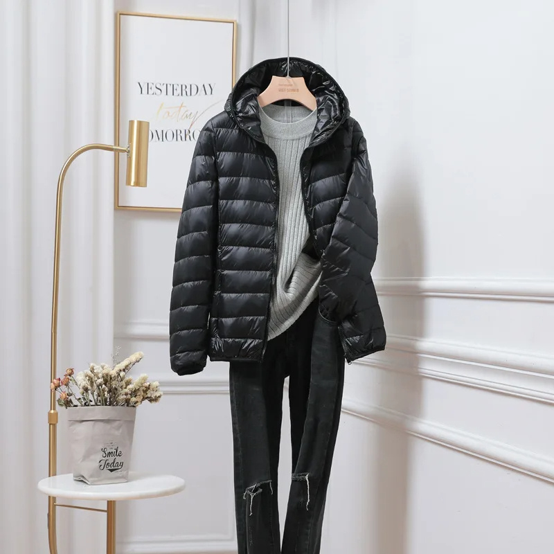 Woman wearing a black ultralight hooded puffer jacket, walking outdoors in winter.