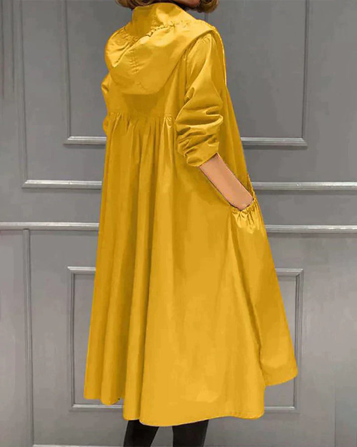 Fashionable women's knee-length rain jacket with hood, versatile outerwear for unpredictable weather.