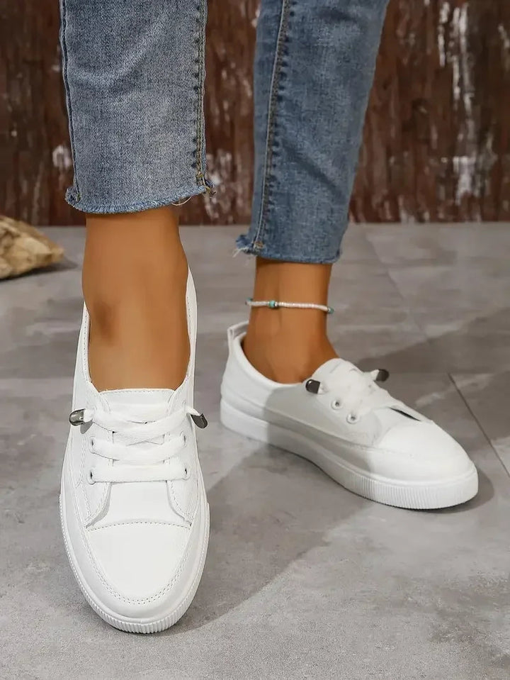 Comfortable women's flat lace-up sneakers in white, ideal for versatile everyday casual wear. Stylish round toe.