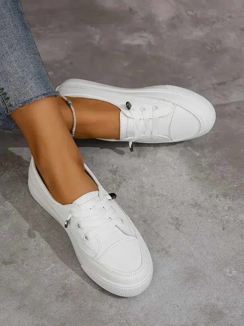 Practical women's white lace-up flat sneakers, providing all-day comfort and a casual look for various outfits.
