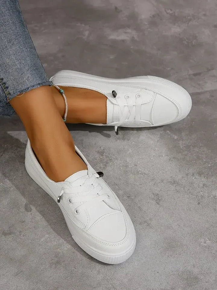 Practical women's white lace-up flat sneakers, providing all-day comfort and a casual look for various outfits.