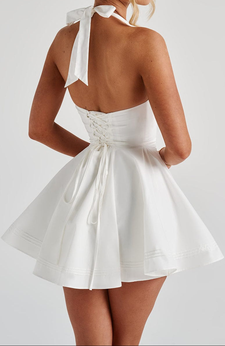 Elegant sleeveless white mini dress with a v-neck halter design for evening wear.