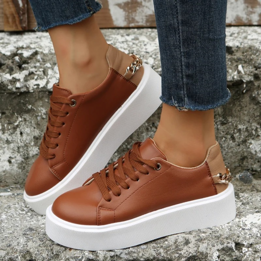 Women's white leather fashion sneakers with stylish metallic chain detail. Trendy & comfortable walking shoes.