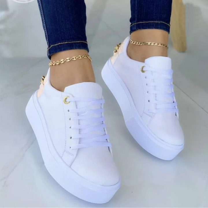 Trendy women's white leather walking shoes with metallic chain. Stylish and comfortable casual footwear.