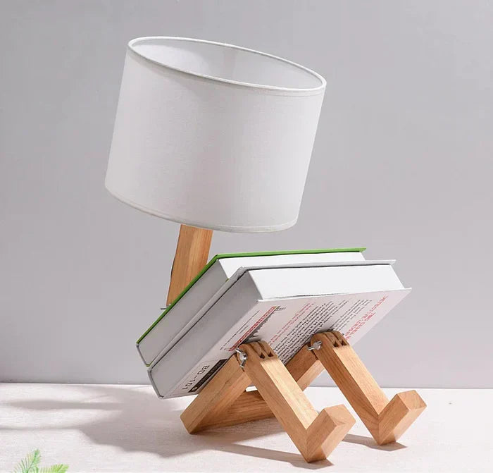 Stylish wooden robot table lamp, modern decor, provides ambient light & book storage.